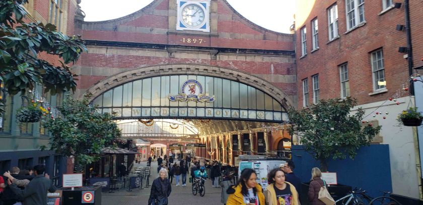 Entrance to Windsor Royal Shopping Centre with pedestrians walking underneath the arched sign.