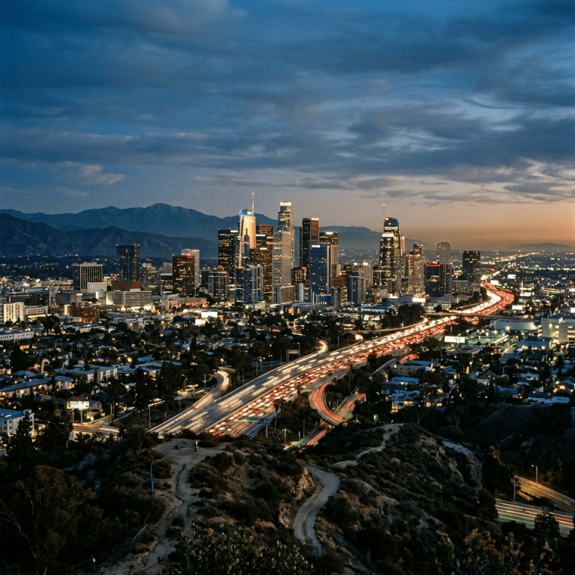 Downtown Los Angeles skyline with high-rise buildings and freeway traffic at dusk